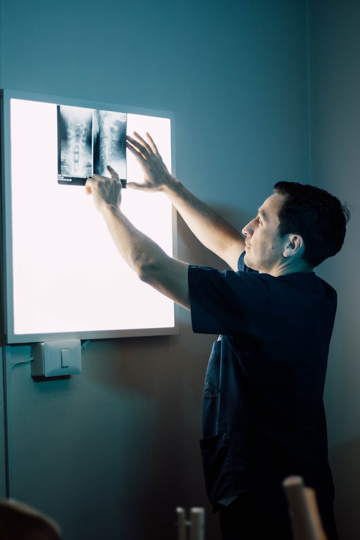A healthcare worker studying an X-ray image on a lightbox in a clinic.